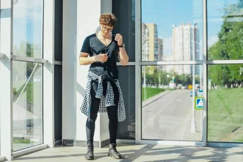 Distant plan of young man standing next to big windows at metro station. Foto stock