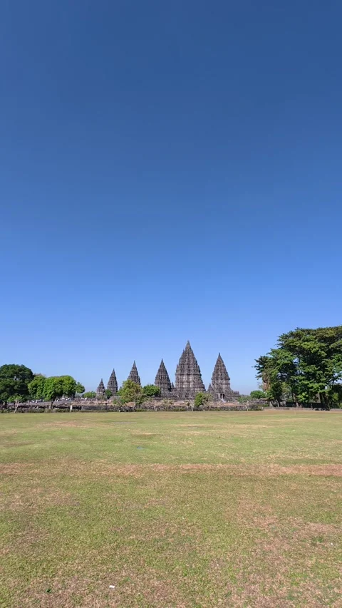 Distant Prambanan Temple spires rise across a broad grassy field beneath a .. Vídeo Stock 341546852