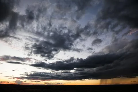 Distant rainstorm at sunset over the grassy plains of Mashatu Botswana Foto stock