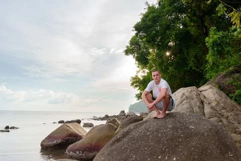 On a distant rock washed by the waves, a young man enjoys the silence and power 写真素材