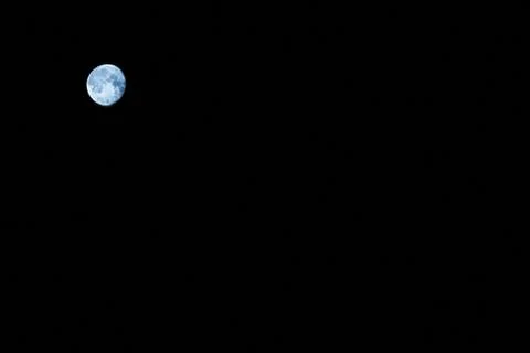 A distant round moon on a black background .Texture or background Stock Photos