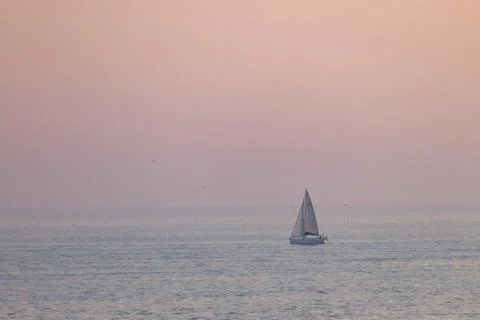 Distant Sailboat at Sunset Stock Photos