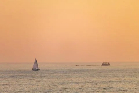 Distant Sailboat at Sunset Stock Photos