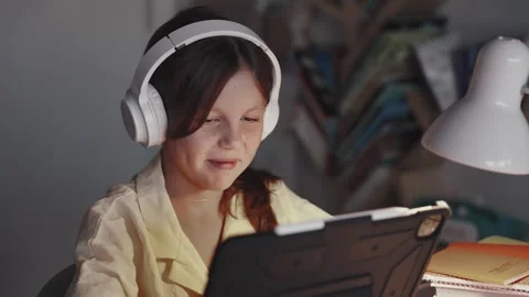 Distant School Learning Concept. Girl in Headphones Uses Tablet Computer Stock Footage 255888500