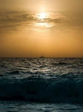 A distant ship sailing in an open sea on sunset Stock Photos