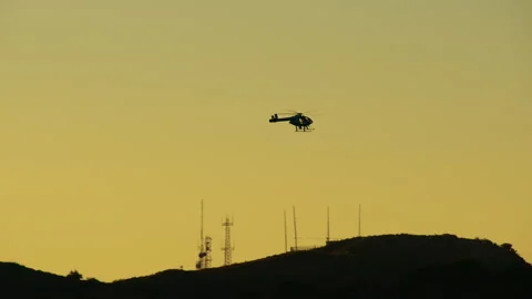A distant shot of a helicopter flying just above the mountain Stock Footage 282001371