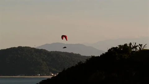 Distant silhouette of a paraglider soaring above the Atlantic Ocean between Video stock 315482870