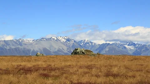 Distant snow capped mountains with grassy fields in foreground. New Zealand. Stock Footage 34343783