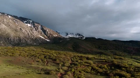 Distant snow-capped peaks stand against a cloudy sky Видео 338199887