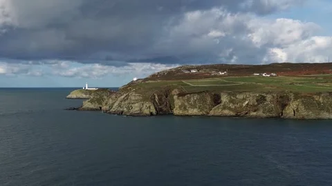 Distant South stack lighthouse aerial view left across rocky cliff shore of Stock Footage 321896892