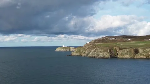Distant South stack lighthouse aerial rising view of rocky cliff shore of Stock Footage 321942380