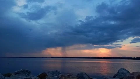 Distant Storm Clouds and Rain Shaft over River at Sunset Stock Footage 342559793