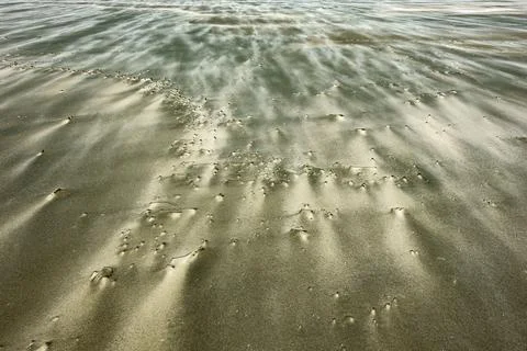 Distant storm clouds and windblown patterns with wind driven sand blowing a.. Stock Photos
