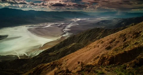 Distant storms brew rain squalls across the desert floor of Death Valley. Stock Footage 236862186