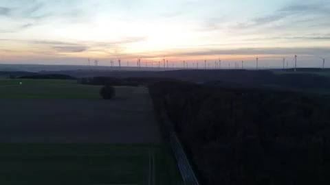 Distant sunset wind farm beside road and forest edge Stock Footage 331215137