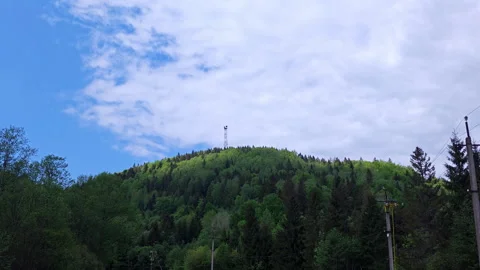 Distant view of 75m telecommunication tower on green mountain peak Video stock 337952733