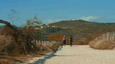 Distant view from behind of two people walking in the middle of the hills. Stock Footage 218471010