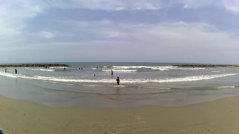 A distant view of children playing on the beach on a very sunny day. Stockbeeldmateriaal 89015007