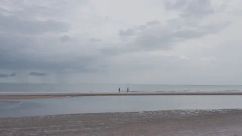 Distant View of Couple Walking One After Another on Beach Stock Footage 337534625