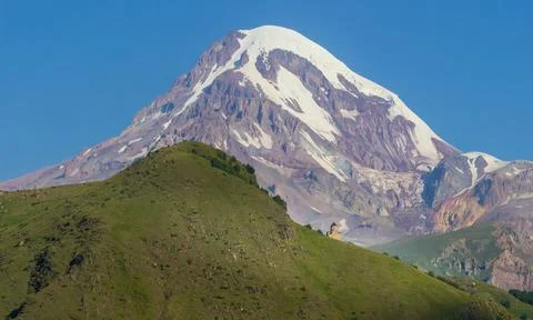 Distant view on Gergeti Trinity Church in Stepansminda, Georgia. Clear sky above Stock Photos