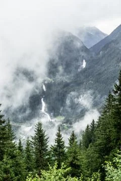 Distant view of the Krimml Waterfalls between trees in Austria Stock Photos