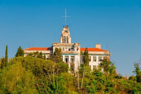 Distant view of an old abandoned building with red roof surrounded by green.. Stock Photos