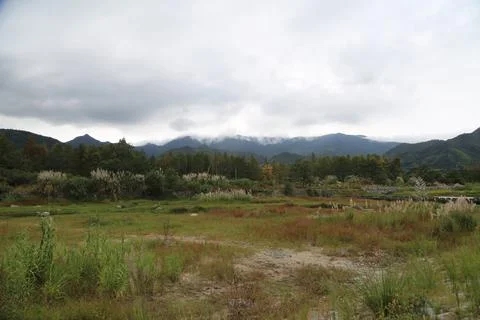 The distant view from an open field , with a mountain range and cloudy sky. Stock Photos