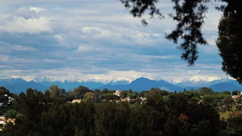 Distant view of orange villas surrounded by green trees with the mountains on Stock Footage 308705136