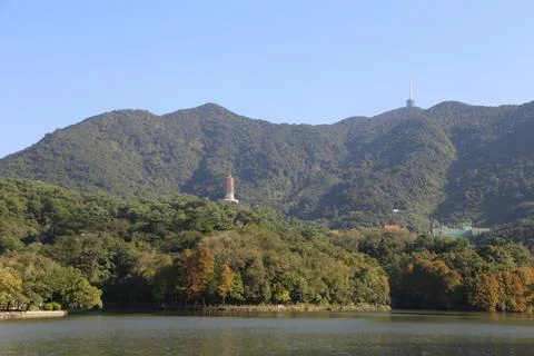 A distant view of the peak, surrounded by green mountains and trees on both.. Foto stock