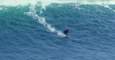 Distant view of pro surfer riding on wild ocean wave near jet ski drivers Stock Footage 156627210