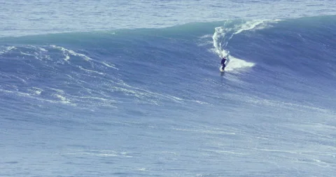 Distant view of professional surfer riding huge ocean wave during sunny day Stock Footage 156624726