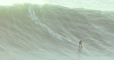 Distant view of professional surfer riding wild ocean wave during sunset Stock Footage 156629642