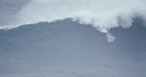 Distant view of professional surfer surfing in ocean with huge wave behind them Video stock 157709364