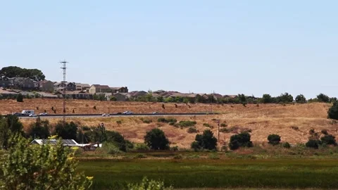 Distant View Of Traffic On Freeway With Wetlands And Housing Stock Footage 313684424