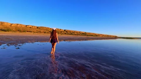 Distant View of Woman Walking in Shallow Lake Stockbeeldmateriaal 344818997