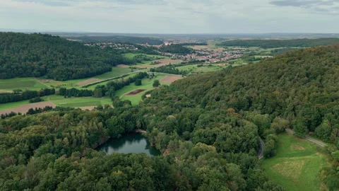 A distant village with a castle and a small lake in between green hills Stock Footage 248089445