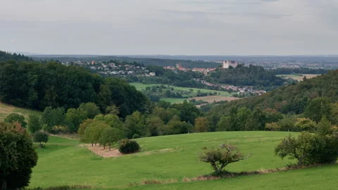 A distant village with a castle in between green hills and fields Stock Footage 248091393