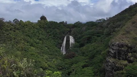 Distant waterfall cascading down a lush green mountain cliff on Kauai Stock-Footage 347826165