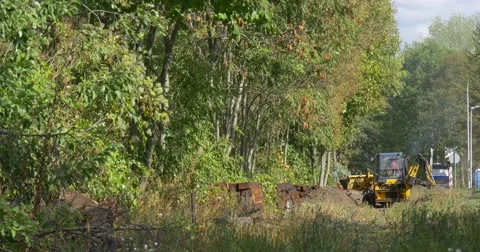 Distantly Workers Are Working Digging Yellow Excavator is Digging Unloads the Stock Footage 55113220