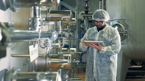 Distillery worker is checking a unit with pipes and reservoirs Stock Footage 102732610