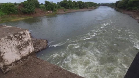 A distinct stone training wall projects from the riverbank directly into a surgi Video stock 342477373