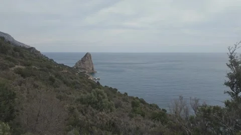 Distinctive Sea Stack Beside Rugged Sardinian Coastal Hills Stock Footage 337564024