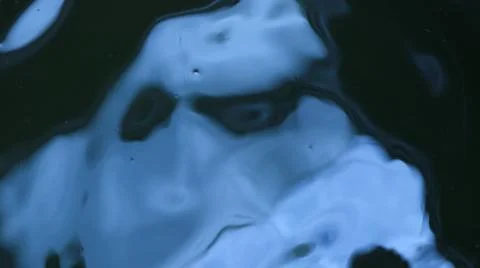 Distorted blue reflection of the sky on dark water Foto stock