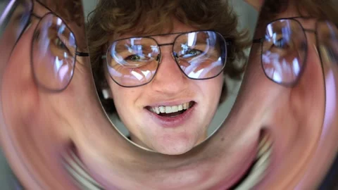 Distorted closeup of a laughing man with glasses surrounded by warped reflection Stock Footage 312981931