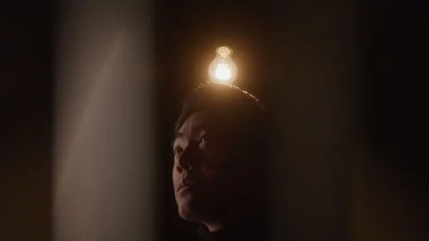 Distorted Headshot of Light Bulb Turning on Above Young Man in Dark Room Stock Footage 270305040