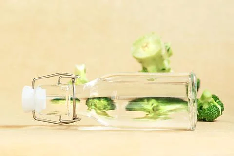 Distorted reflection of broccoli cabbage through water bottles on beige backg Stock Photos