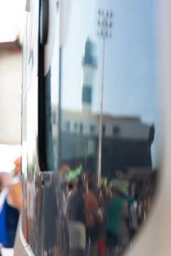 Distorted reflection of the Farol da Barra lighthouse and the crowd on a ve.. Stock Photos