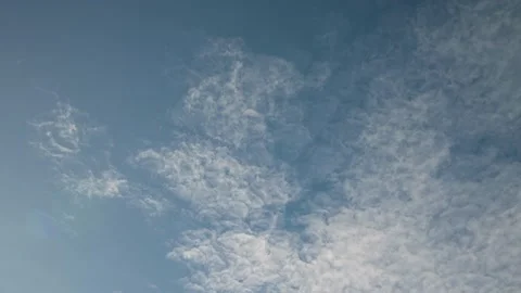 Distorted shapes of white wispy clouds move through a blue sky Stock Footage 142398903