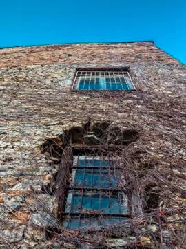 Distorted wall of an old stone building with two bar window panes and walls c Stock Photos