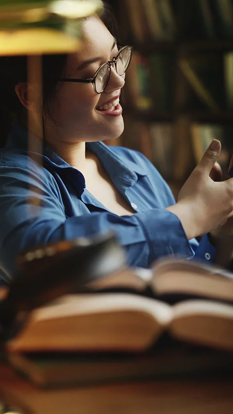 Distracted Asian woman scrolling through social network app instead of studying Stock Footage 331883853